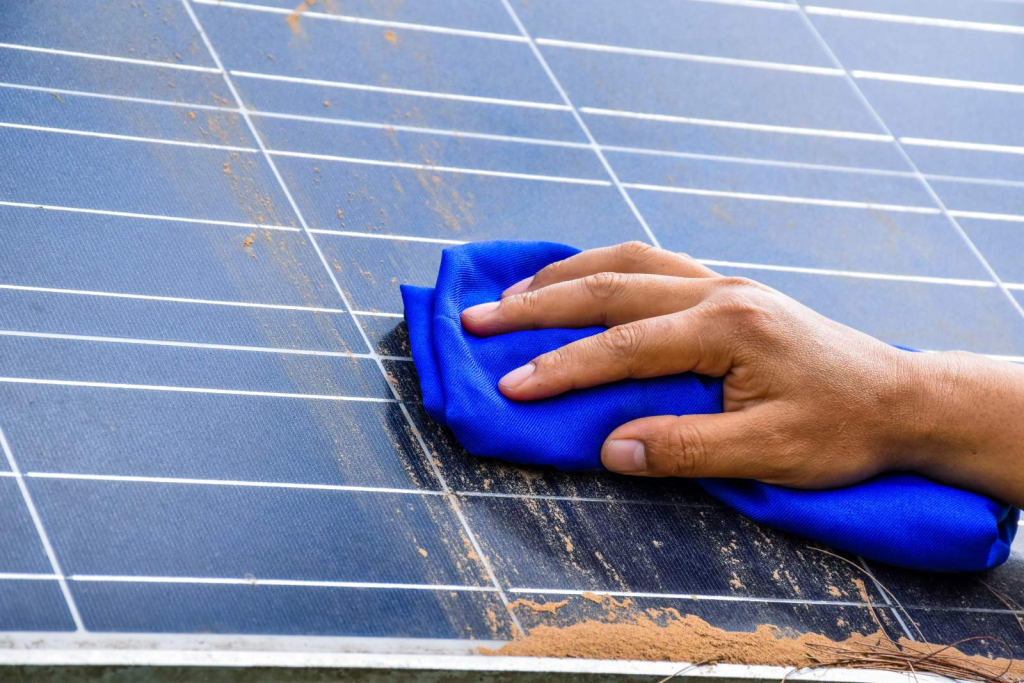 person wiping pollen off solar panels